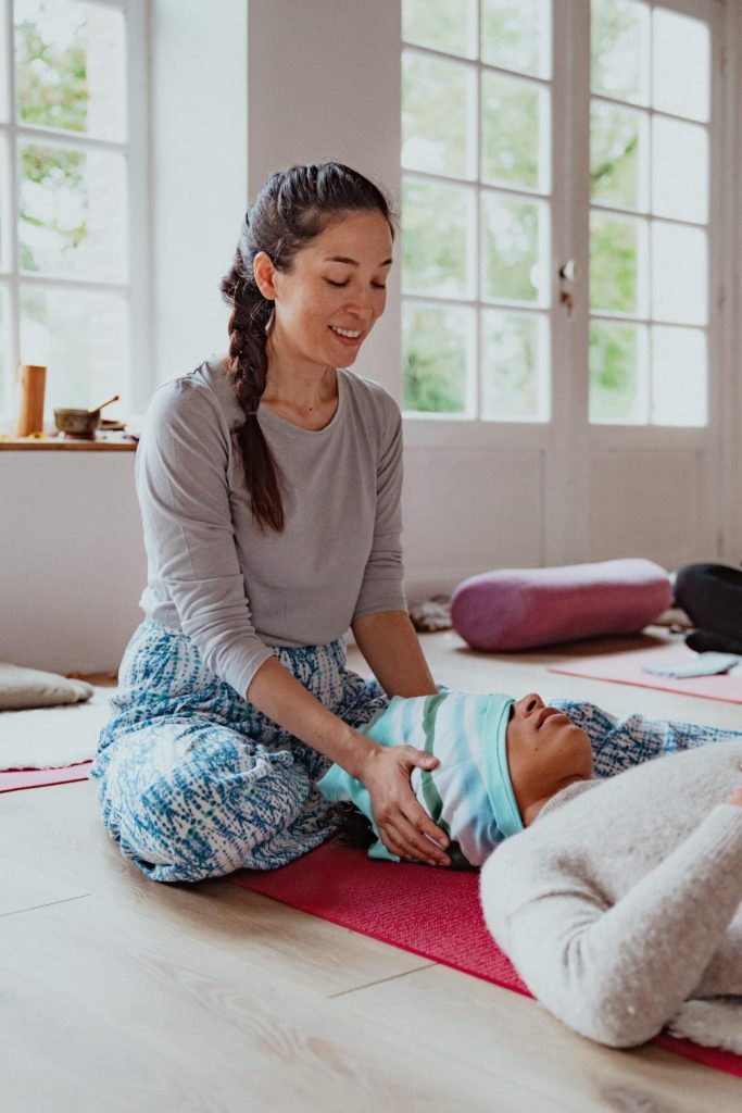 Lors d'une formation, Marisa Bai (doula) montre les gestes à effectuer pour étirer la nuque à l'aide d'un tissu japonais appelé Tenugui.
