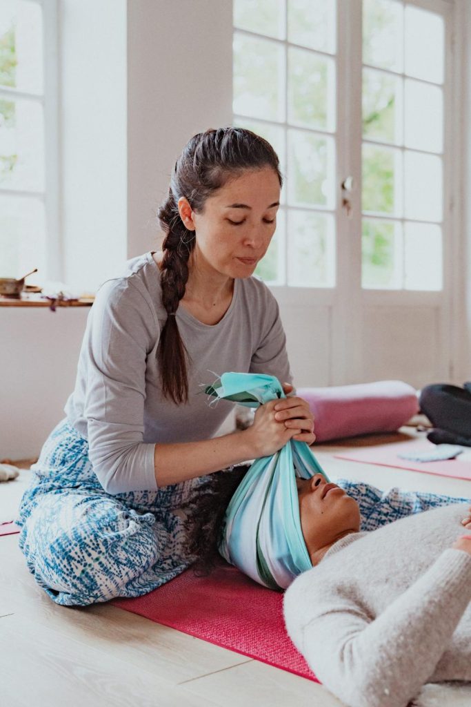Lors d'une formation, Marisa Bai (doula) montre les gestes à effectuer pour étirer la nuque à l'aide d'un tissu japonais appelé Tenugui.
