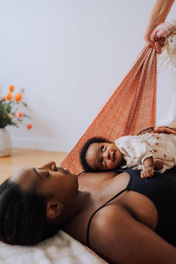 Marisa Bai (doula) pratique un massage Rebozo sur une jeune maman et son bébé.