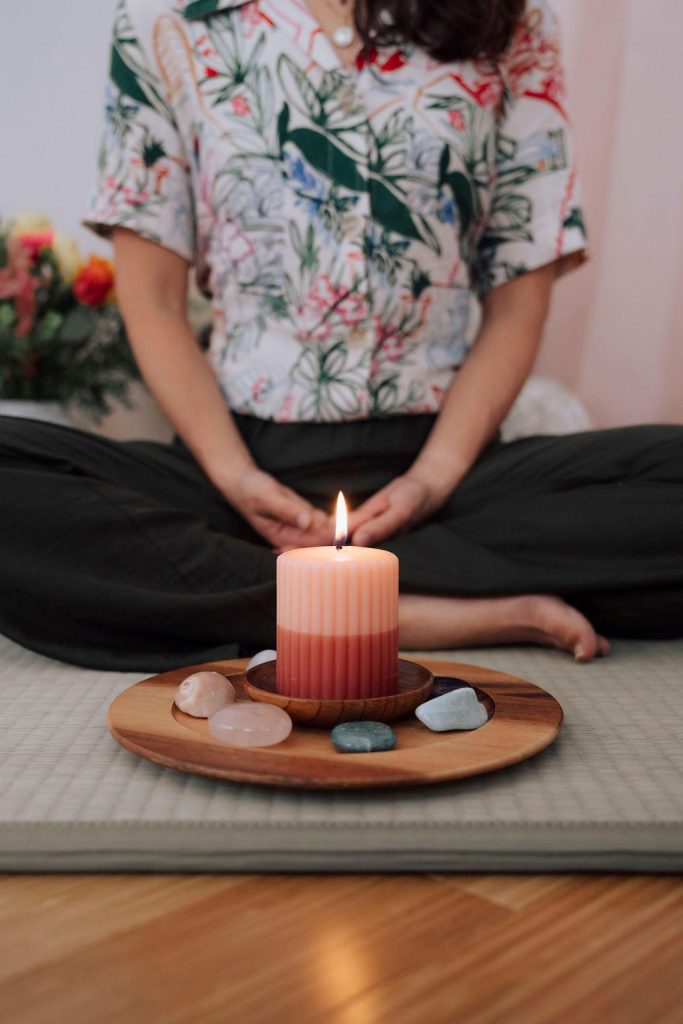 Une bougie posée au sol, entourée de pierres et de cristaux, dans un moment de méditation 