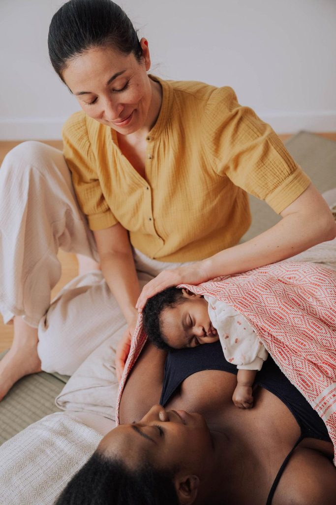 Marisa Bai (doula) pratique un massage Rebozo sur une jeune maman et son bébé.