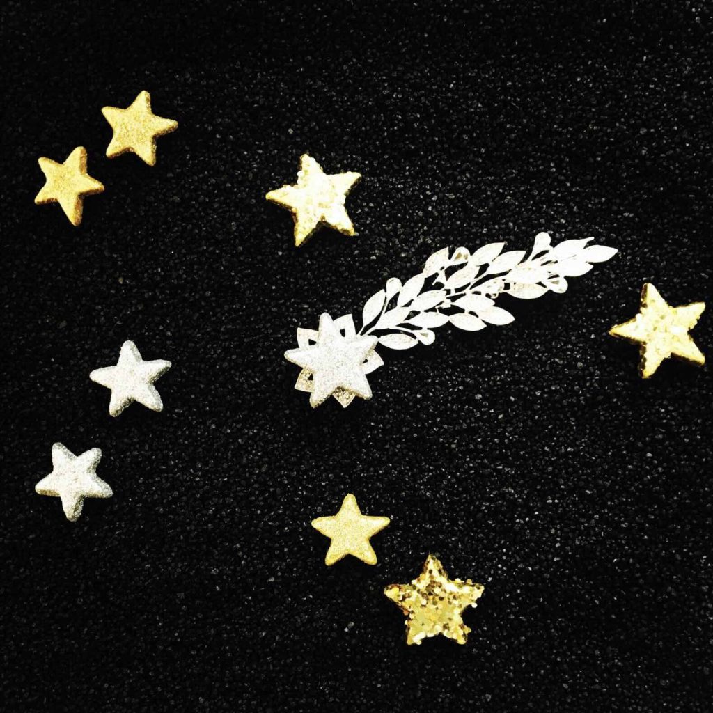 Séance d'une Thérapie par le Jeu de sable : des étoiles dorées et argentées posées sur un sable noir