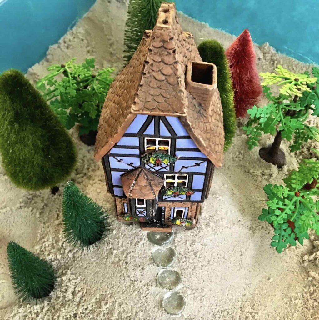 Séance d'une Thérapie par le Jeu de sable : une maison et un jardin posés sur le sable