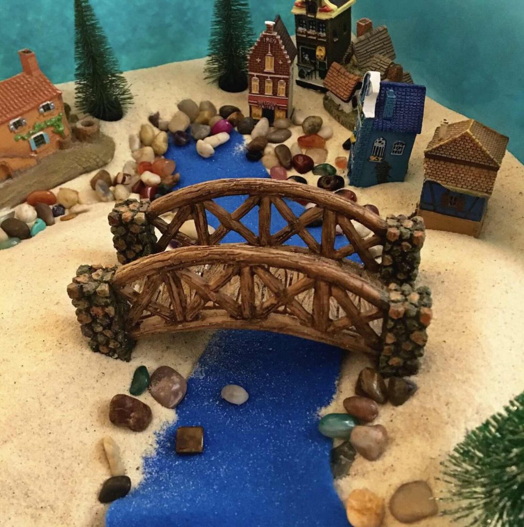Séance d'une Thérapie par le Jeu de sable : un pont reliant deux zones dans un village