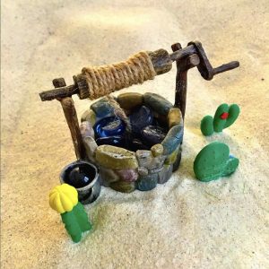 Séance d'une Thérapie par le Jeu de sable : un petit puits et des cactus posés sur le sable