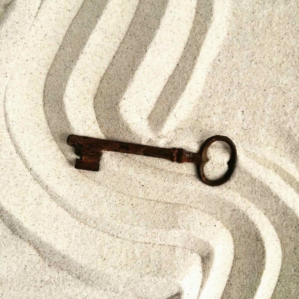 Séance d'une Thérapie par le Jeu de sable : une clé posée sur le sable qui a été strié