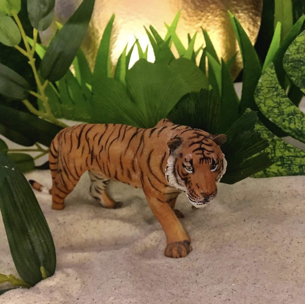 Séance d'une Thérapie par le Jeu de sable : un lion entouré de plantations, sur le sable