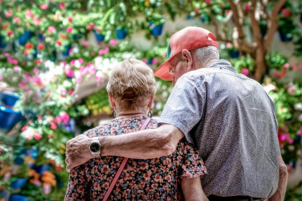 Couple de personnes âgés vu de dos. L'homme tient sa femme par l'épaule dans un geste de tendresse.