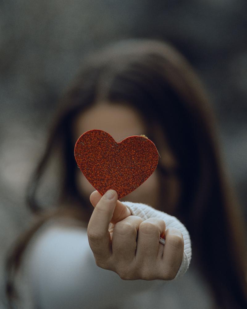 Un coeur rouge tenu dans la main d'une jeune femme, en guide de gratitude et de remerciement en conscience