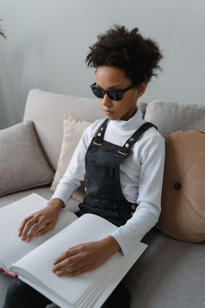 Image représentant une petite fille handicapée lisant un livre en braille avec son doigt