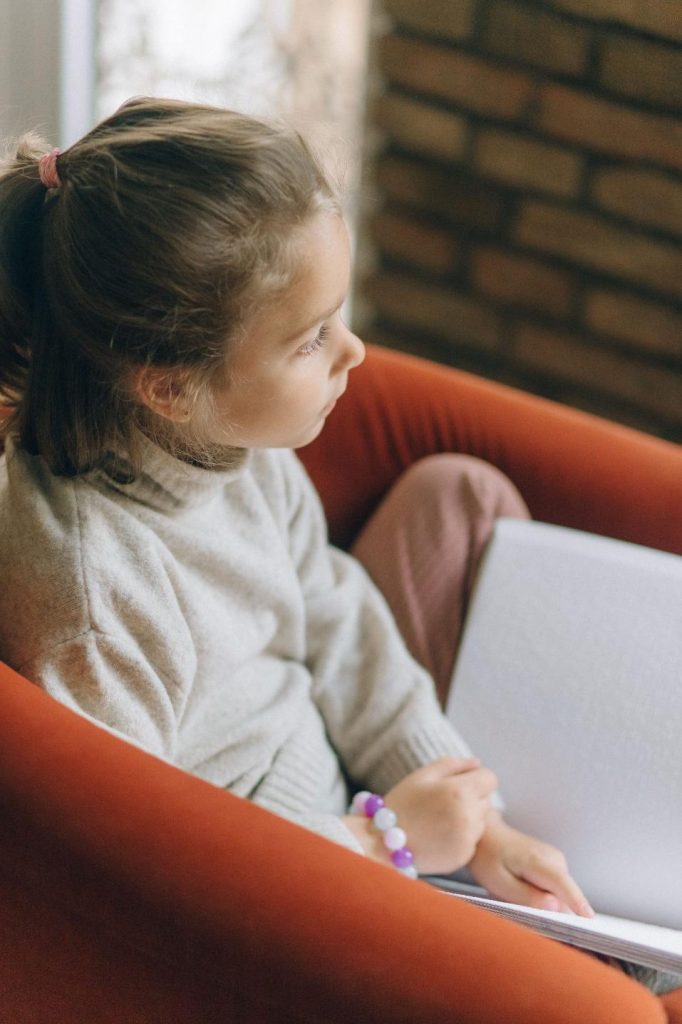 Image représentant une petite fille handicapée lisant un livre en braille avec son doigt