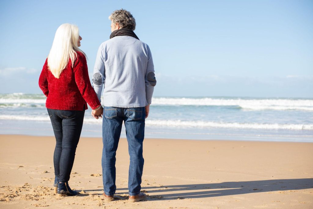 Un couple senior sur la plage qui se regarde tendrement et se tient par la main : cette photo illustre le fait de retrouver l'amour après un veuvage